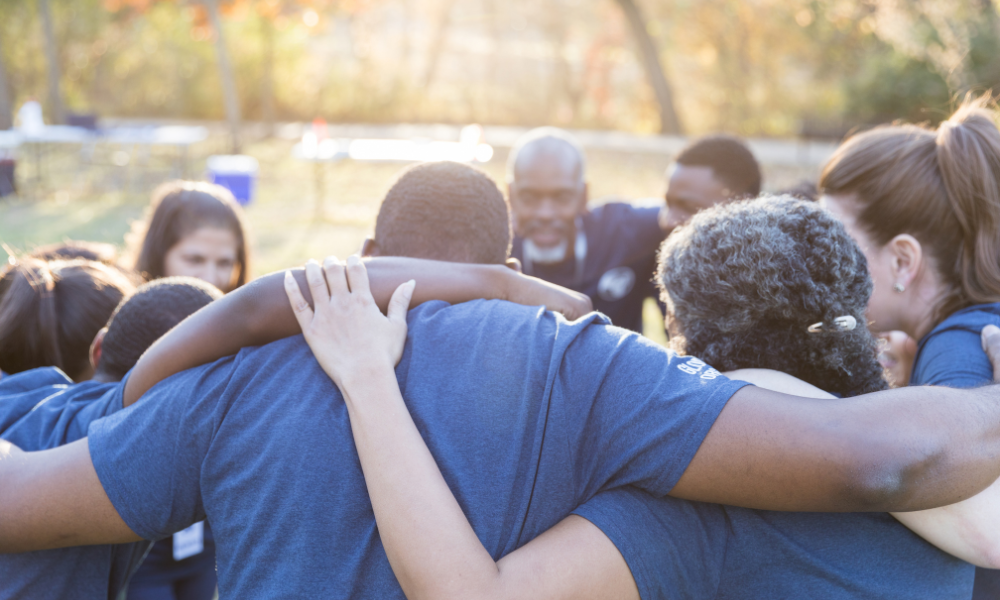What Is Vto? 4 Important Benefits 3 Volunteers in a park in a huddle circle, building teamwork.