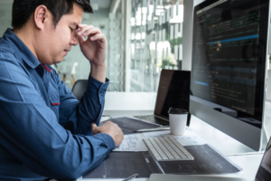 Top 10 Hiring Tips Every Business Owner Needs To Know 2 a photo of a person looking at computer software and suffering from a headache