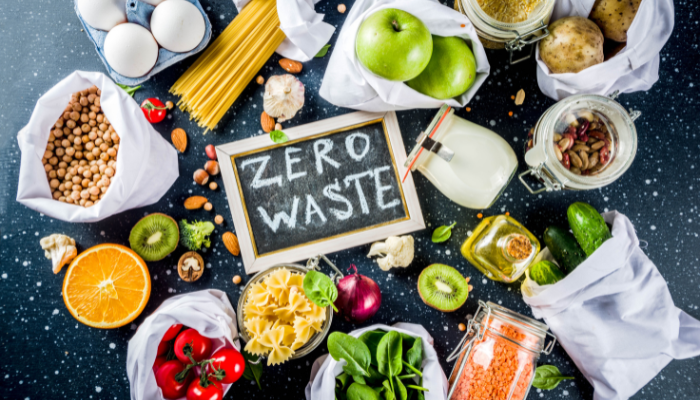 Fresh produce and grains around a chalkboard that reads ZERO WASTE.