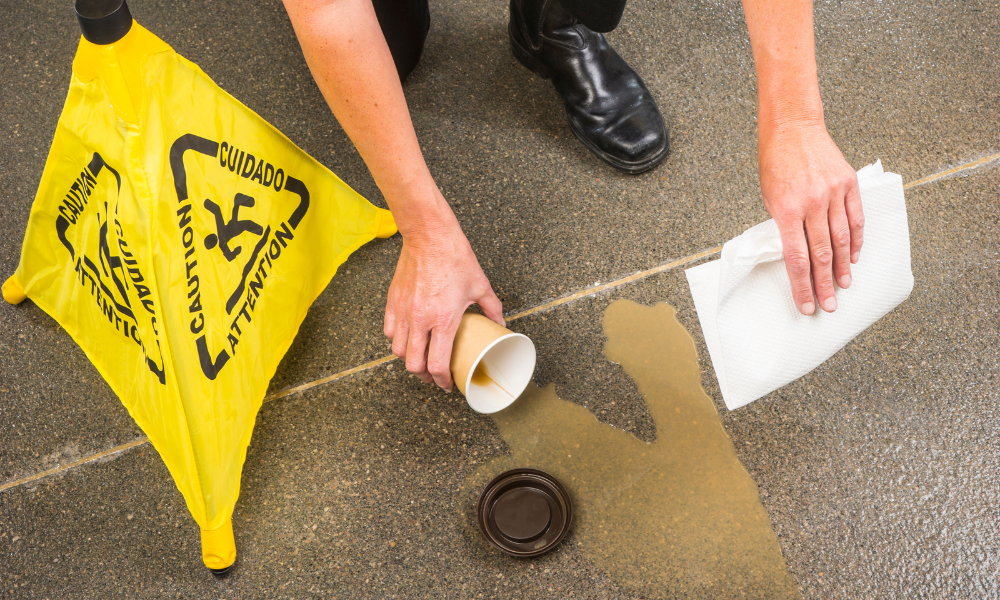 An employee cleaning up a dangerous drink spill on the sidewalk.