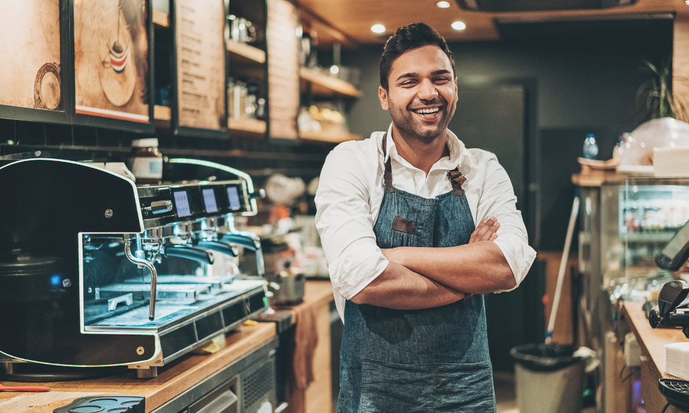 Smiling male barista in apron.
