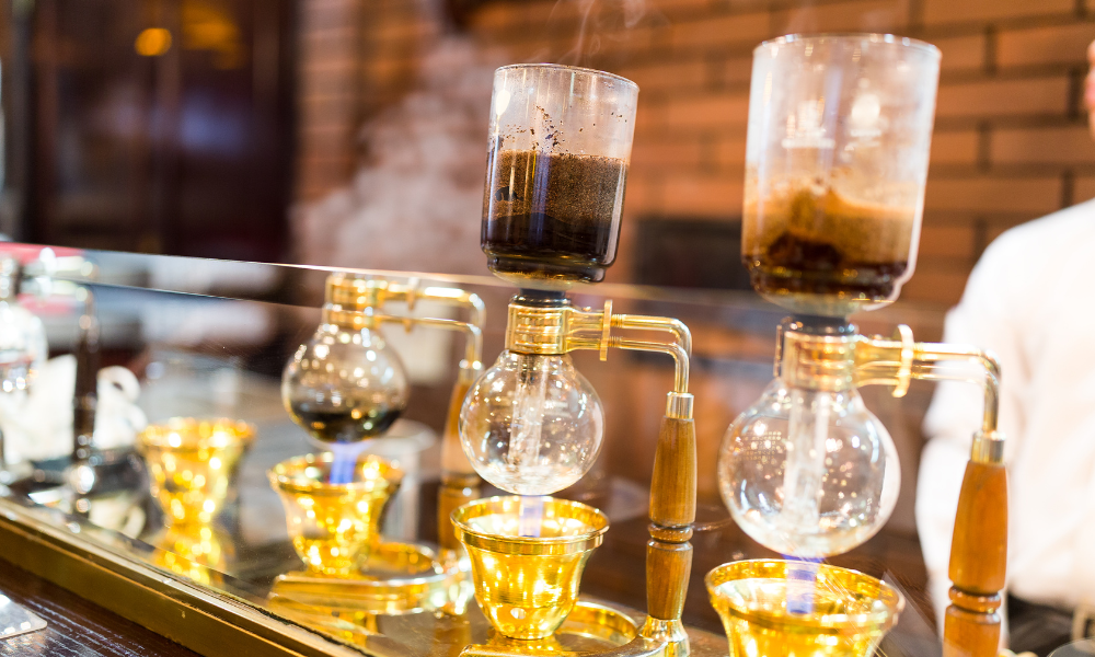 10 Ways To Brew Coffee In Your Restaurant 7 Siphon brewers on a counter in a cafe.