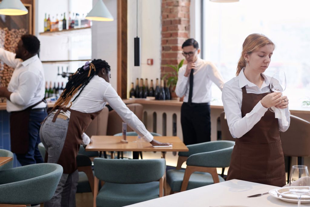 What Restaurant Sales Forecasting Actually Does For Your Labor Costs 1 Restaurant staff preparing the dining room before service — restaurant sales forecasting helps managers schedule the right team for every shift