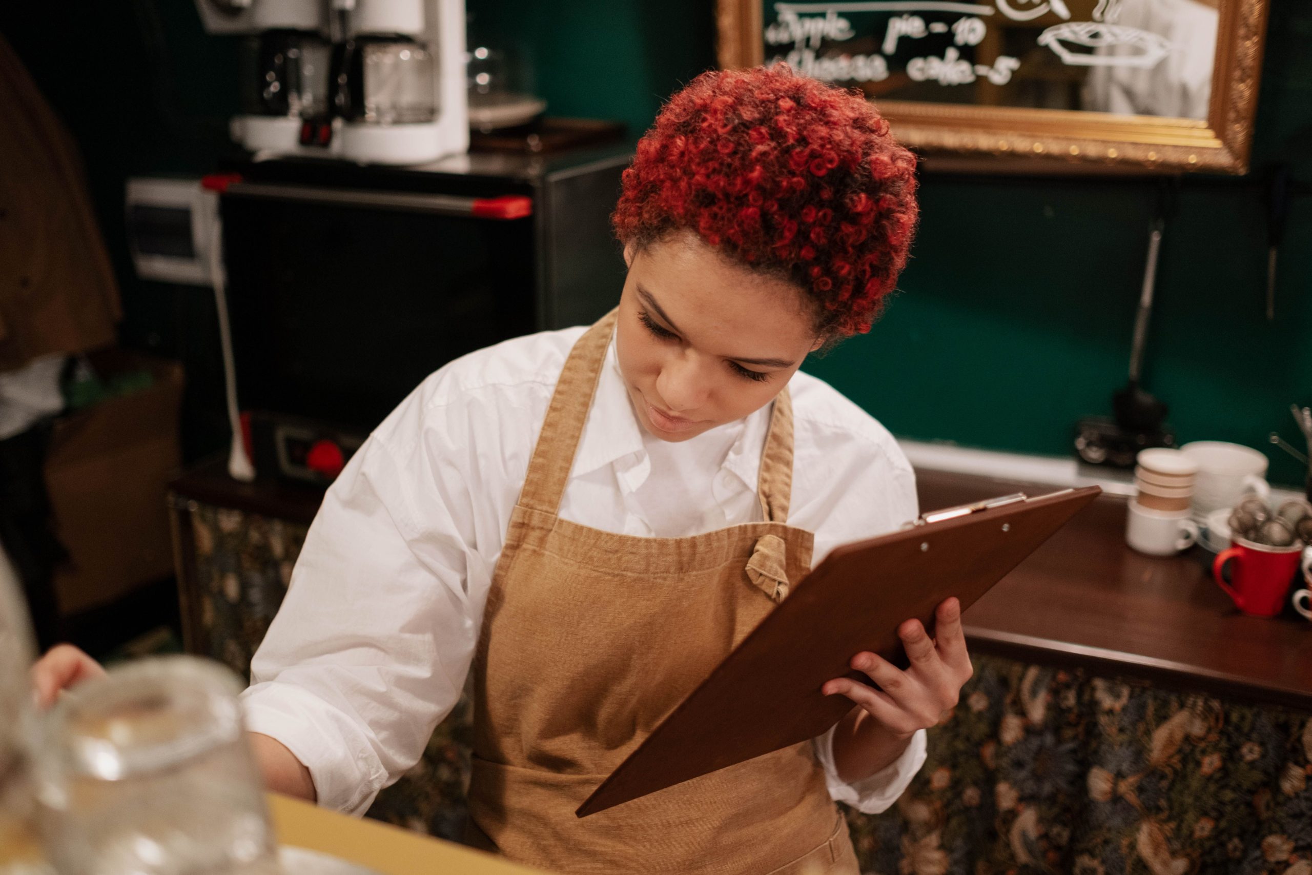 Restaurant manager reviewing staff schedule on a clipboard, preparing to handle last-minute employee callouts