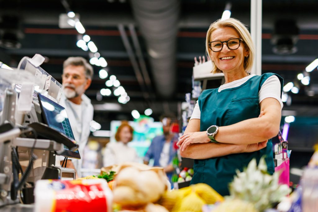 Independent Grocery Labor Costs: Why Top Operators Earn 12X The Net Profit 2 senior cashier smiling at checkout counter in supe 2026 01 09 09 42 26 utc.